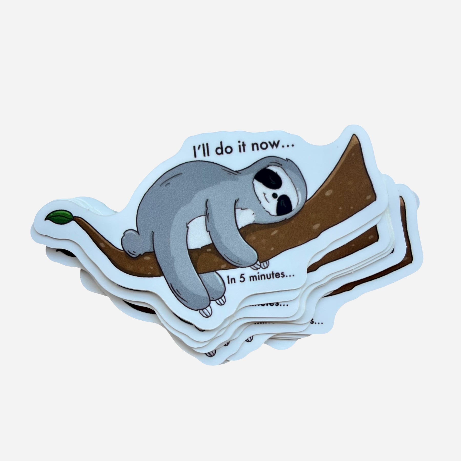 Stack of stickers with a sloth on a branch and humorous text, on a light blue background.